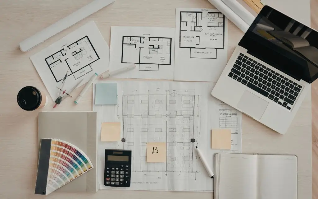 table with a couple of plans, a computer, notebook and a calculator illustrating how to build a career plan