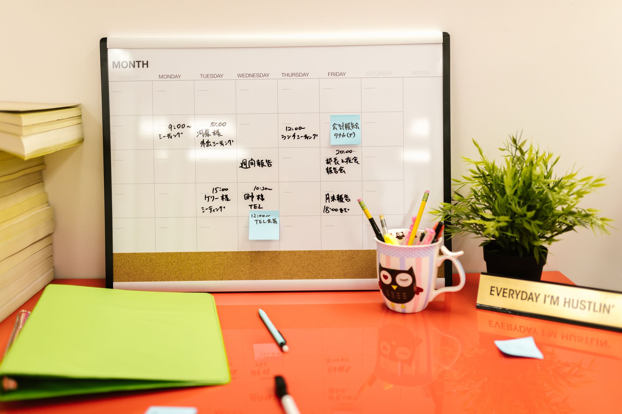 Neat workspace with a calendar, plant, and stationery on a red desk.