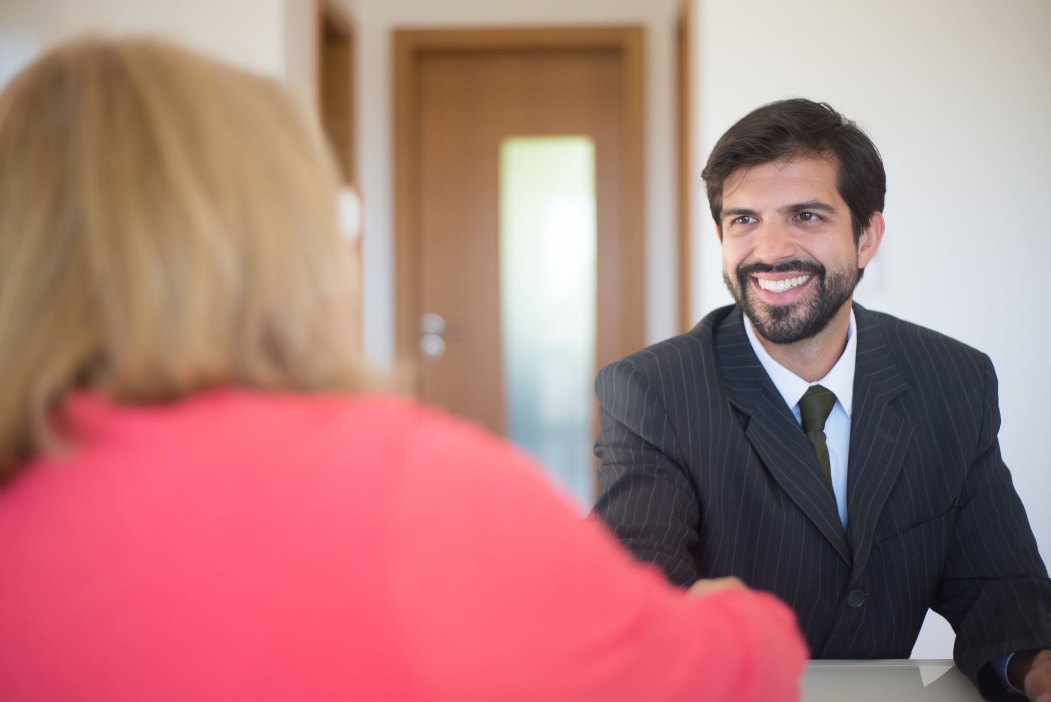 Professional businessman smiling and handshaking during a meeting in an office setting.